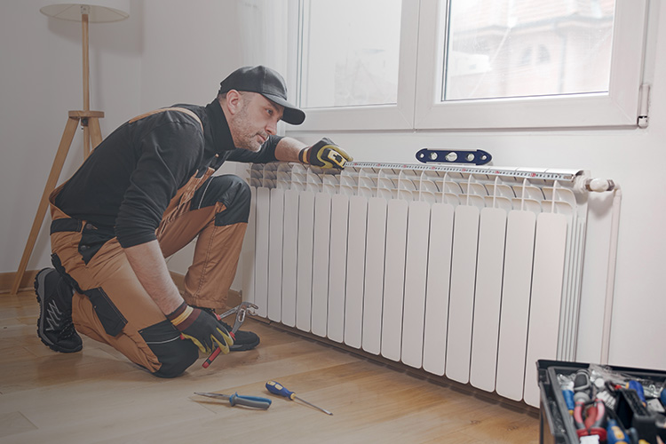 Heizungsinstallateur arbeitet an Heizkörper