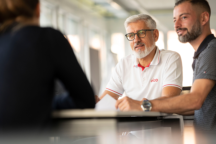 Mitarbeitende im Gespräch während einer Besprechung in einem modernen Büro- und Arbeitsumfeld bei ELCO.