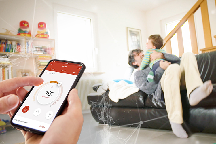 Person hält Smartphone in der Hand mit geöffnetet Remocon Net App. Im Hinergrund spielt ein Vater mit seinem Sohn.